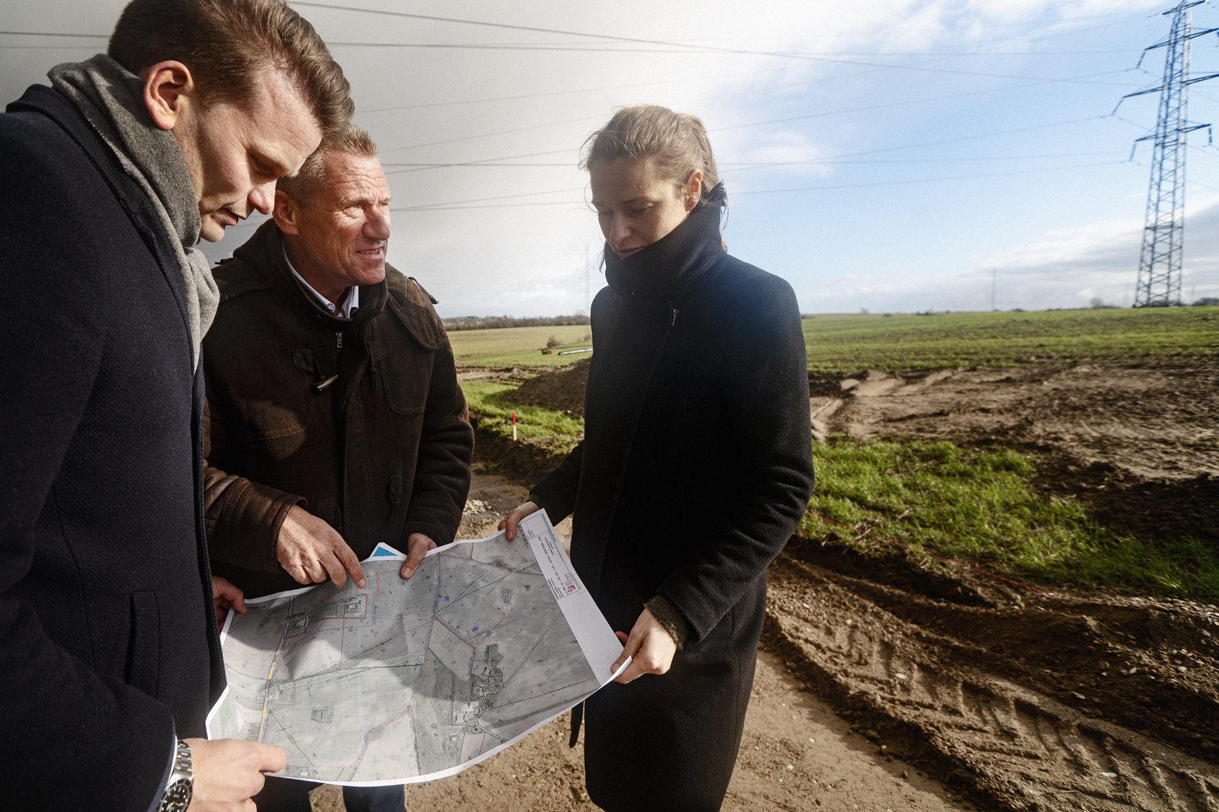Three people looking at a map near a pylon